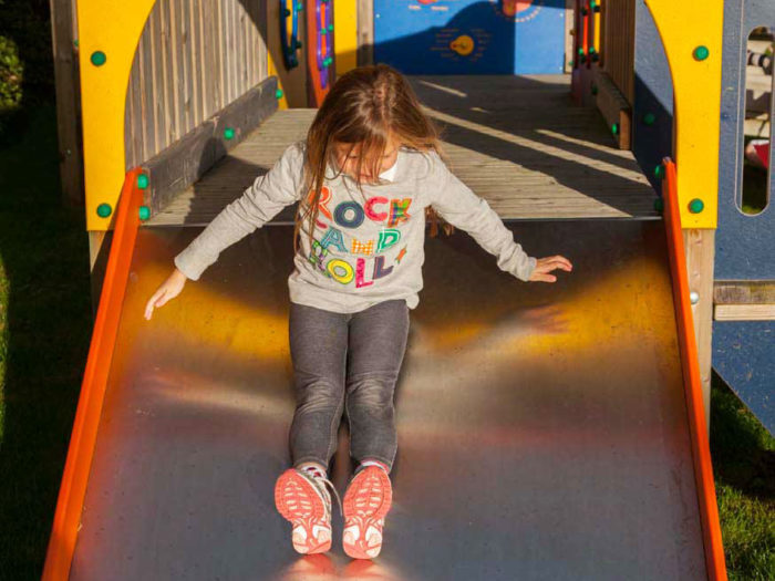 young child using a village playground slide